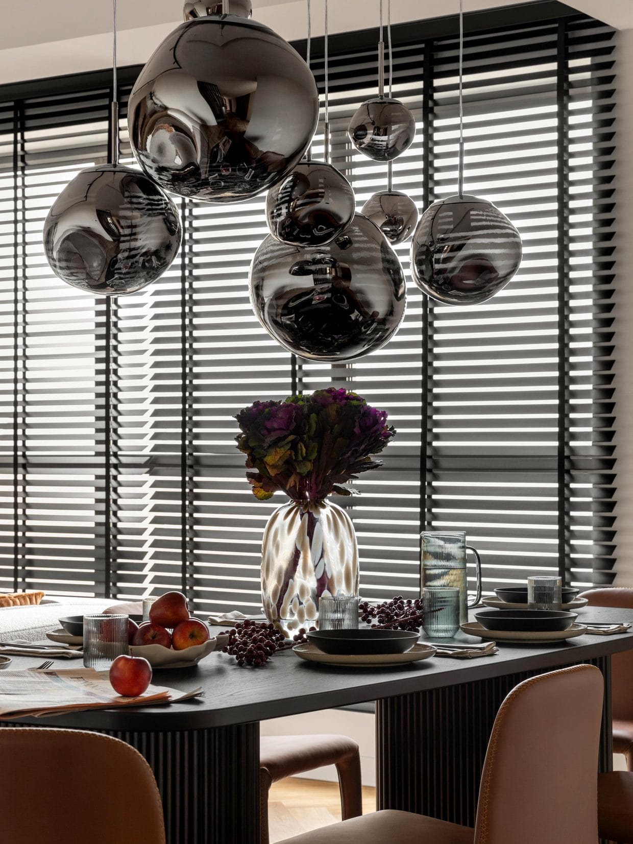 Dubai penthouse dining room by Anna Arsentyeva: smoked glass pendants over a black ribbed table, late light through timber blinds
